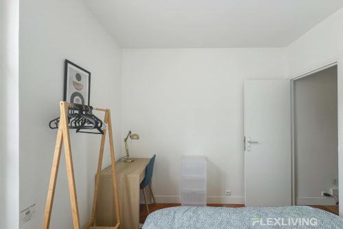 une chambre avec un lit et un mur blanc dans l'établissement Flexliving - room - Augereau, à Paris