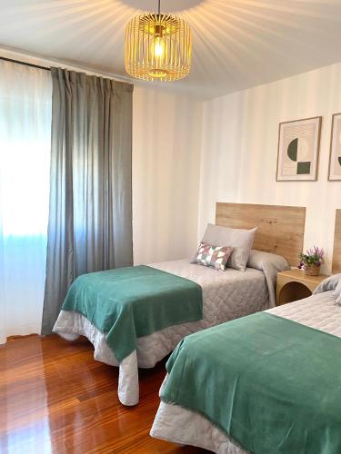 a bedroom with two beds and a chandelier at Aloha T in Porriño