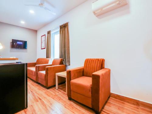 a living room with two chairs and a flat screen tv at Super Townhouse CASA GRAND in Hyderabad