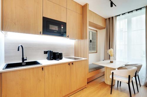 une cuisine avec des armoires en bois, un évier et une table dans l'établissement Beautiful Apartment - 1BR-4P - Le Marais, à Paris
