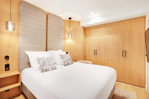 - une chambre avec un grand lit blanc et des placards en bois dans l'établissement Beautiful Apartment - 1BR-4P - Le Marais, à Paris