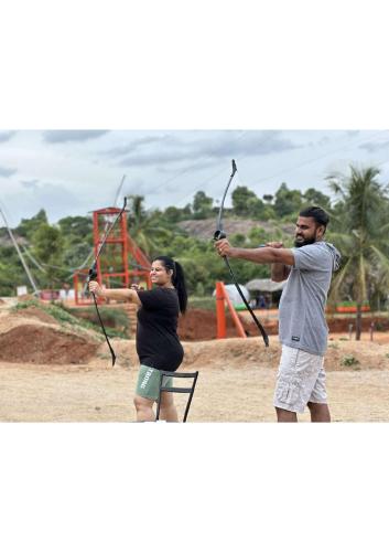 a man and a woman holding onto a bow and arrows at Ravishing Retreat Resort in Rāmanagaram
