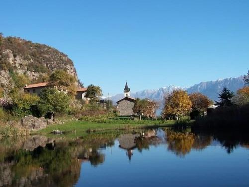 a reflection of a church in a river with a church at Casa vacanze "INCANTO DEL LAGO" in Corna