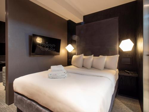 a hotel room with a large bed with white sheets at Apartment Bloc in Birmingham