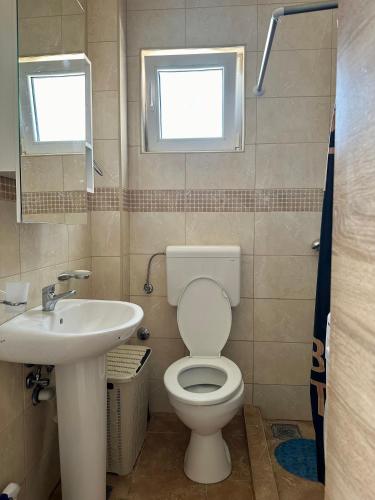 a bathroom with a toilet and a sink and two windows at Kronos in Budva