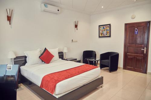 a bedroom with a bed with two chairs and a door at Guest Wharf - Centre Ville in Pointe-Noire