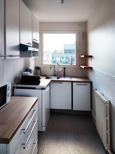 Elle comprend une petite cuisine avec des placards blancs et une fenêtre. dans l'établissement Flexliving - room - Villon, à Paris