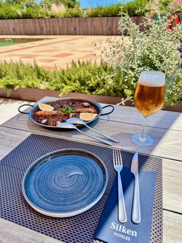 a table with a plate of food and a glass of beer at Silken Platja d'Aro in Platja  d'Aro