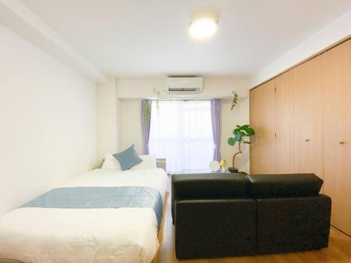 a bedroom with two beds and a couch and a window at B3 Guest House ユニオン新大阪,新大阪,十三,梅田近く 長期滞在にも最適 in Osaka