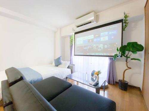a living room with a couch and a large screen at B3 Guest House ユニオン新大阪,新大阪,十三,梅田近く 長期滞在にも最適 in Osaka