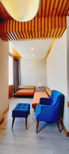 a hotel room with a bed and a blue chair at Hotel Rewa Ladakh in Leh