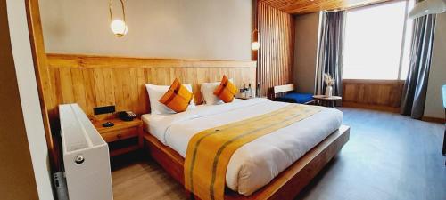 a bedroom with a large bed with orange and yellow pillows at Hotel Rewa Ladakh in Leh