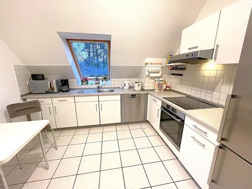 a kitchen with white cabinets and a sink and a window at Wald Ferienwohnung Hamburg 1 in Rosengarten