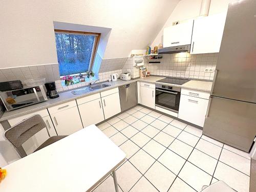 a kitchen with white appliances and a white tiled floor at Wald Ferienwohnung Hamburg 1 in Rosengarten