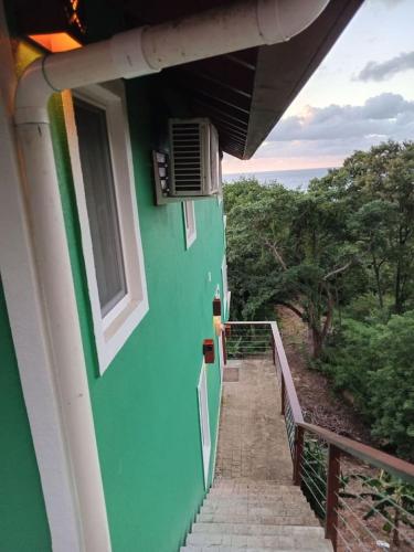 a green building with a staircase leading to a balcony at Palm Luxury King Suite, Pool, ocean views, beach short walk West Bay West End in West Bay
