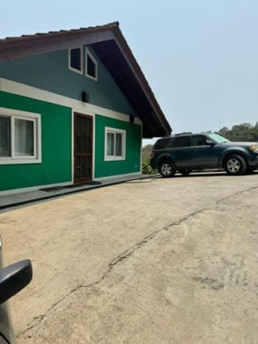 a car parked in front of a green house at Palm Luxury King Suite, Pool, ocean views, beach short walk West Bay West End in West Bay