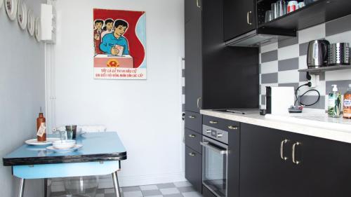 une petite cuisine avec des armoires noires et une table bleue dans l'établissement Bel Appartement de Charme - Centre Ville - Quartier du Boulingrin - Gare, à Reims