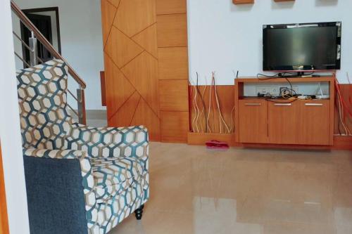 a living room with a chair and a television at Zealots Cyber Hills Villa, Kozhikode - Calicut in Kakkayam