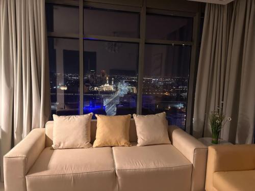 a white couch in a room with a large window at VIP Luxury Premium Apartment in Manama