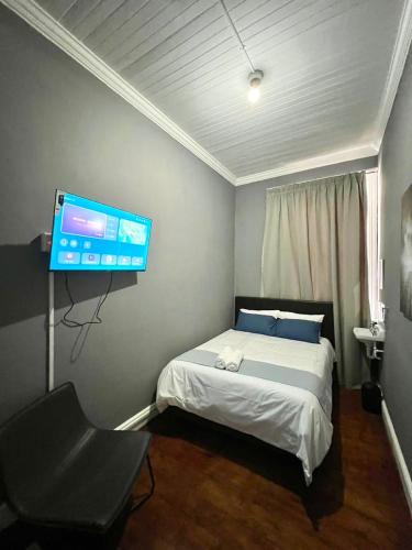 a bedroom with a bed and a flat screen tv at CapePod Sea Point in Cape Town