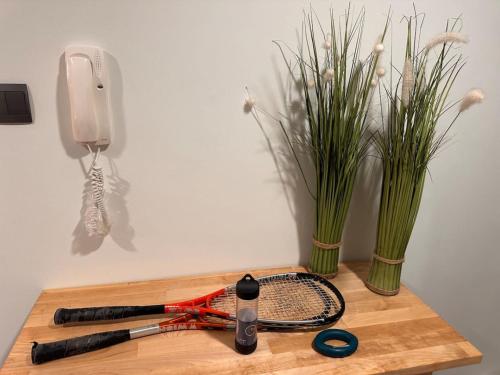 a tennis racket on a table with a phone and flowers at VIP Luxury Premium Apartment in Manama