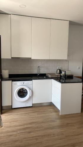 a kitchen with white cabinets and a washing machine at Casinhas Dona Isabel in Arcos de Valdevez