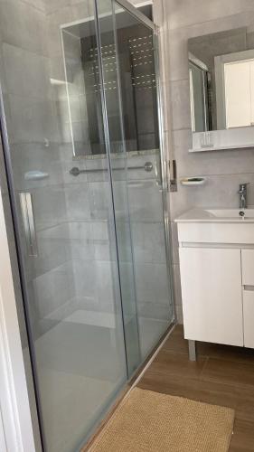 a glass shower in a bathroom with a sink at Casinhas Dona Isabel in Arcos de Valdevez