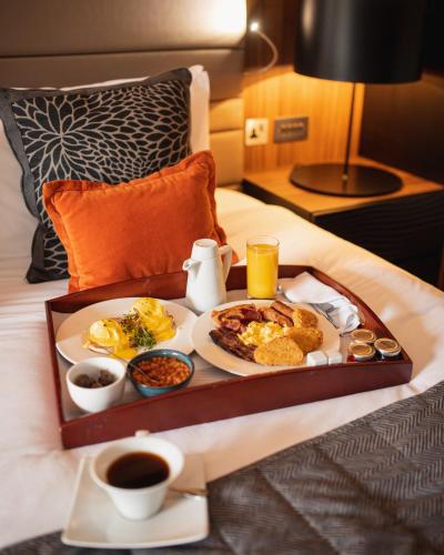 a breakfast tray with breakfast foods on a bed at Crowne Plaza Gerrards Cross by IHG in Beaconsfield