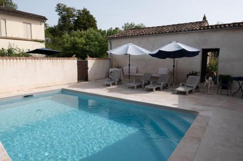 une piscine avec des chaises et un parasol à côté d'une maison dans l'établissement Magnifique Maison de la Rivière, à Saint-Seurin-de-Prats