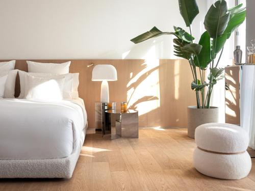 a bedroom with a bed and a chair and a plant at The Roc Club, A Grecotel Hotel to Live in Athens