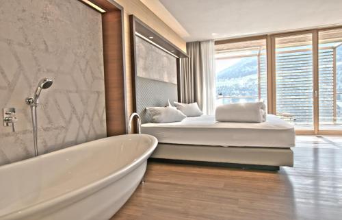 a bedroom with a tub and a bed with a window at B&B Boutique Hotel Burgund in Parcines