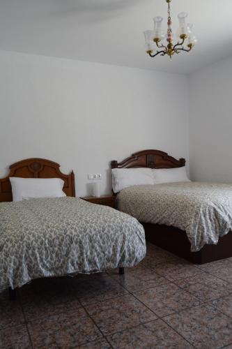 a bedroom with two beds and a chandelier at Casa Rural O Noso Lar in Raspay