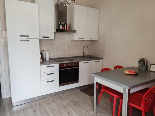 a kitchen with white cabinets and a table with red chairs at BB Ombretta in Valeggio sul Mincio