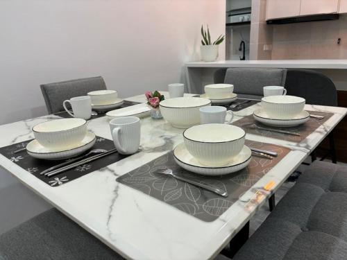 a table with plates and cups on top of it at ANNA AR ANTARA RESIDENCE LAKE VIEW, Putrajaya in Putrajaya
