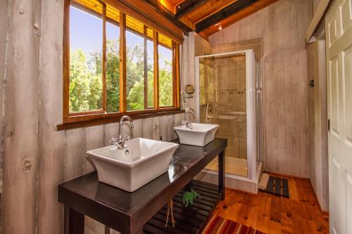 Dois lavatórios numa casa de banho com uma janela em Piesang Valley Lodge em Plettenberg Bay
