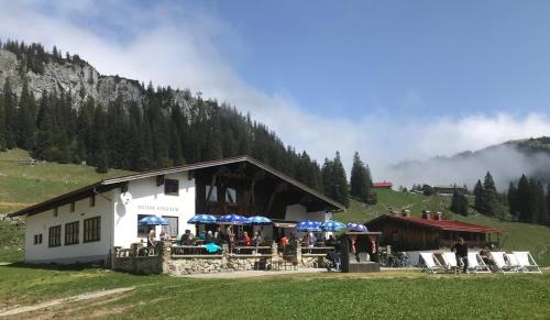 a group of people sitting outside of a building with umbrellas at Untere Firstalm in Schliersee