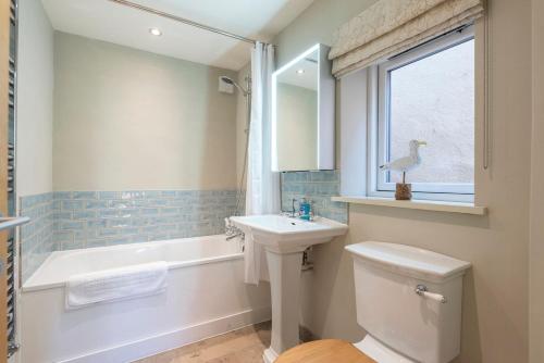 a bathroom with a sink and a toilet and a tub at Captain's Quarters, a ground floor apartment in Aldeburgh in Aldeburgh