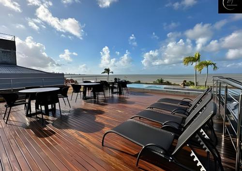 a deck with tables and chairs and a swimming pool at LM Unity Cabo branco in Penha