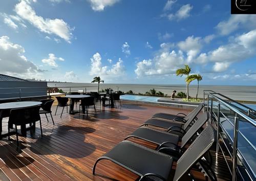a deck with tables and chairs overlooking the ocean at LM Unity Cabo branco in Penha