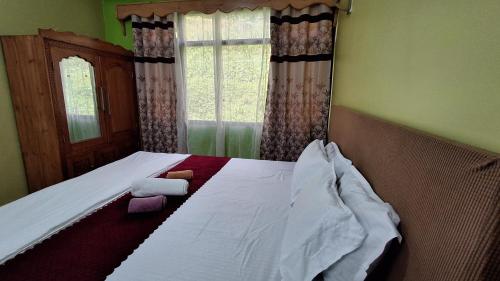 a bedroom with a bed with white sheets and a window at Mantra Inn Lachung in Lachung