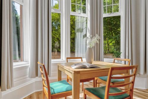 a dining room with a table and chairs and windows at Woodford Street in Mansewood