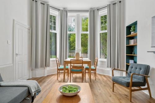 a living room with a table and chairs and windows at Woodford Street in Mansewood