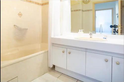 La salle de bains est pourvue d'un lavabo blanc, d'une baignoire et d'une chambre. dans l'établissement APPARTEMENT T2- Terrasse- vue dégagée -Centre ville-Tout à pieds- L Impérial, à Saint-Raphaël