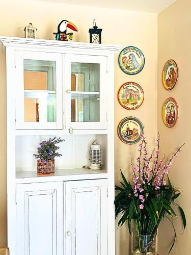 Un armario blanco con un jarrón de flores y platos. en Casas M&G Penedo com vista para a serra, en Penedo