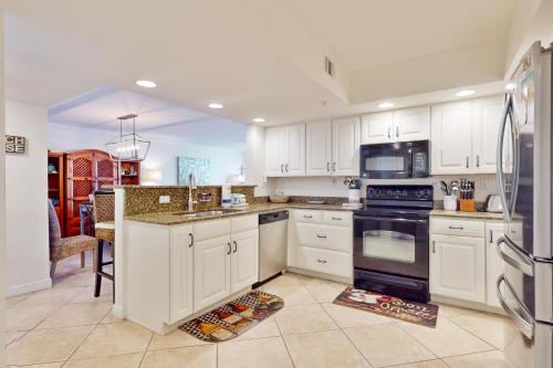 a kitchen with white cabinets and black appliances at SeaSpray East E0122 in Perdido Key
