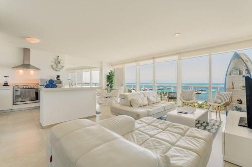 a living room with white furniture and a view of the ocean at MARINA Beachfront 2 BDR by CASA PARAISO in Cancún