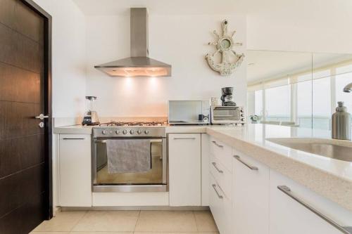 a white kitchen with a stove and a sink at MARINA Beachfront 2 BDR by CASA PARAISO in Cancún