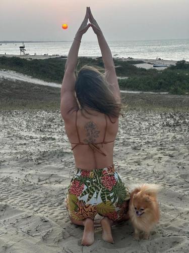 a woman sitting on the beach with a dog at Espetacular Casa de Charme em São Miguel do Gostoso - Salou in São Miguel do Gostoso
