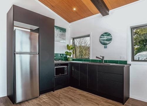 a kitchen with black cabinets and a stainless steel refrigerator at Black Label Retreats in Gisborne