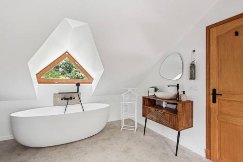 a bathroom with a large white tub and a wooden table at Magnifique Villa, 1H de Paris, Piscine chauffée ! in Labosse